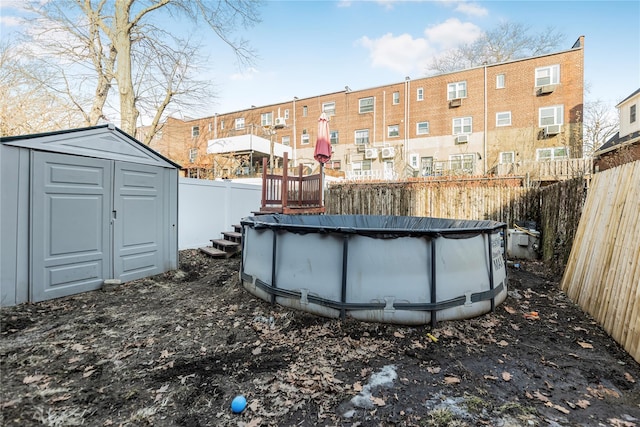 view of yard featuring a storage shed, an outbuilding, fence, and a covered pool