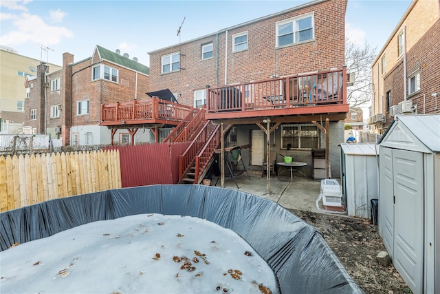 rear view of property featuring an outbuilding, brick siding, a storage shed, a deck, and stairs