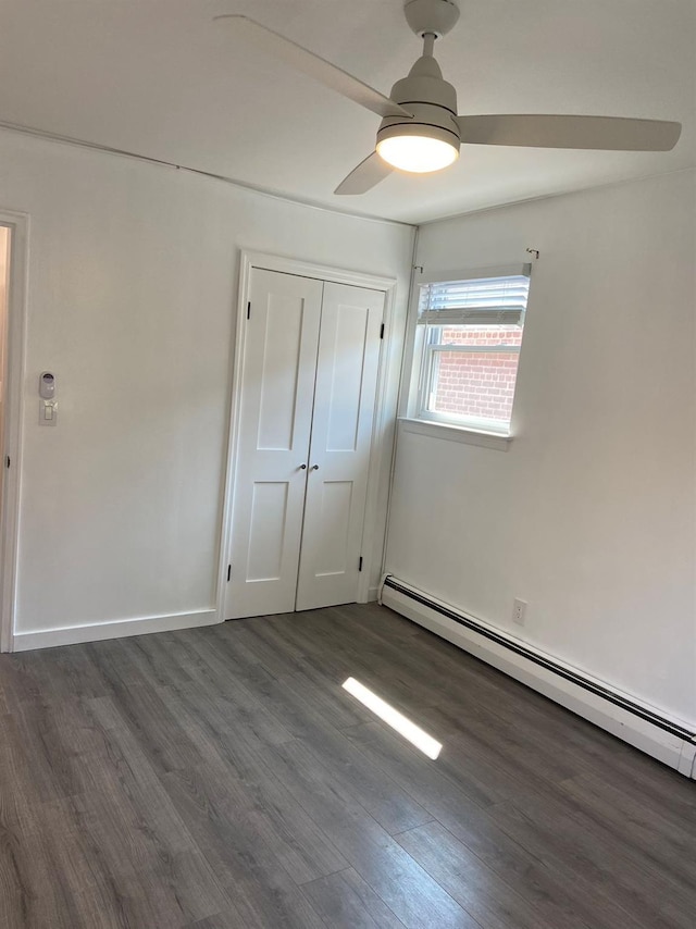 unfurnished room featuring ceiling fan, baseboards, a baseboard heating unit, and dark wood finished floors