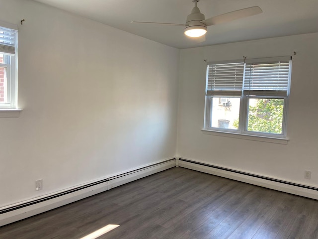 empty room featuring dark wood-type flooring, plenty of natural light, baseboard heating, and a ceiling fan