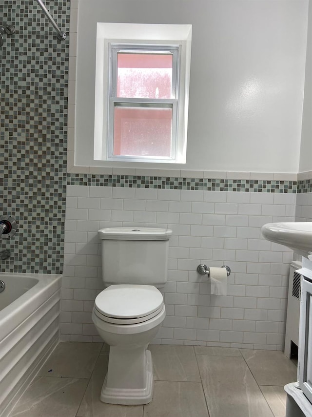 full bath with a wainscoted wall, tile walls, toilet, washtub / shower combination, and tile patterned floors