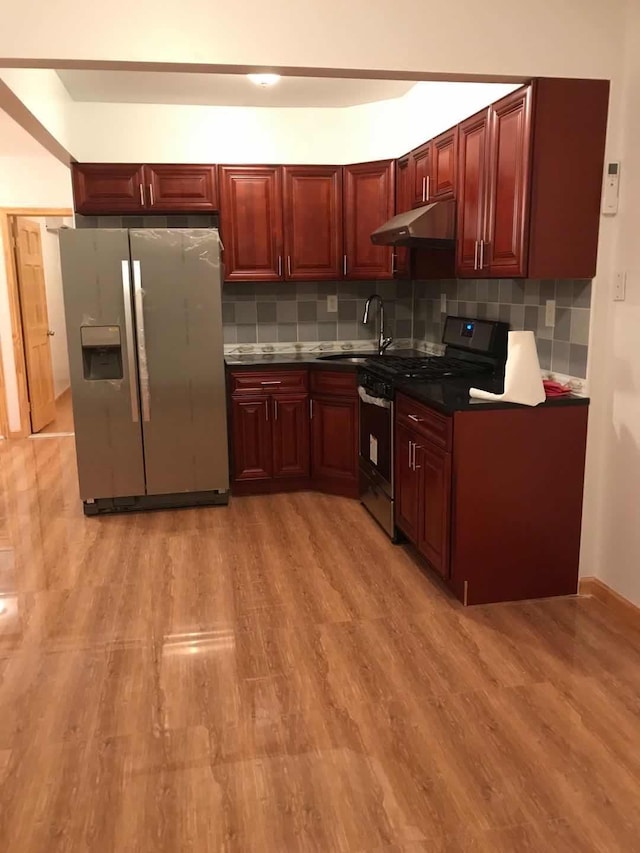 kitchen featuring under cabinet range hood, dark brown cabinets, stainless steel appliances, and a sink