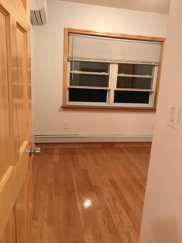 spare room featuring a baseboard radiator, wood finished floors, and a wall mounted AC