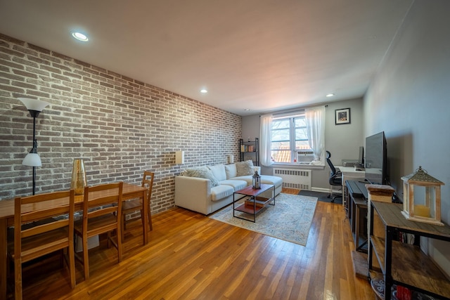 living room with brick wall, radiator heating unit, wood finished floors, and recessed lighting