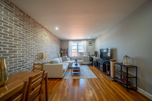 living room featuring recessed lighting, radiator, brick wall, baseboards, and hardwood / wood-style flooring