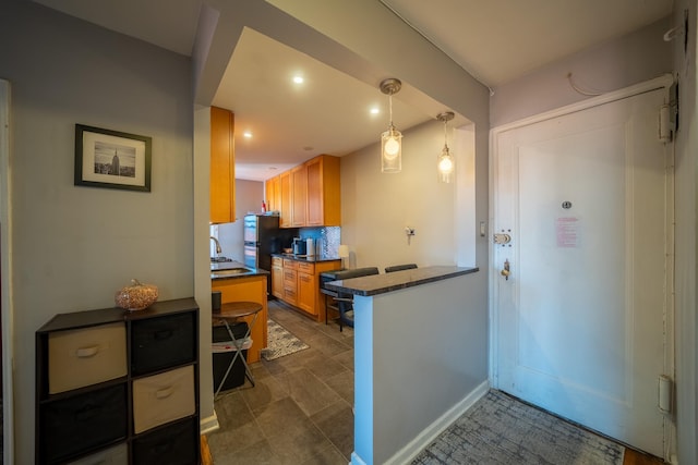 kitchen featuring decorative light fixtures, dark countertops, recessed lighting, backsplash, and a sink