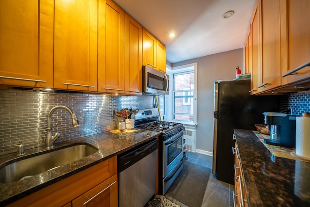 kitchen featuring dark stone counters, appliances with stainless steel finishes, a sink, and tasteful backsplash