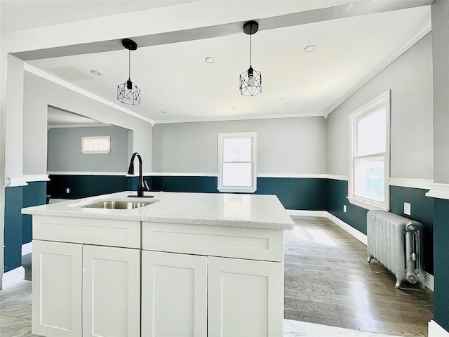 kitchen featuring pendant lighting, a sink, white cabinetry, and radiator