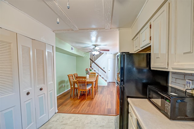 kitchen featuring visible vents, baseboards, light wood-style floors, ceiling fan, and black appliances