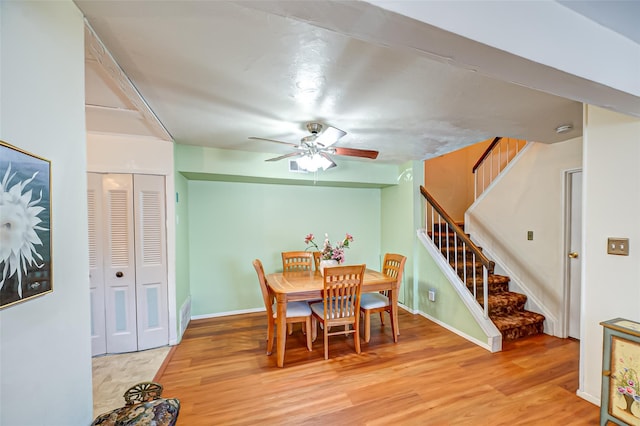 dining space featuring light wood finished floors, stairway, and baseboards