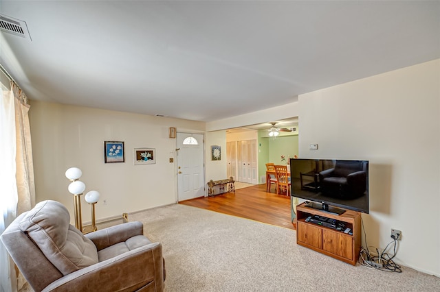 carpeted living area with ceiling fan and visible vents