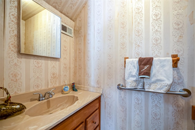 bathroom featuring visible vents, vanity, and wallpapered walls