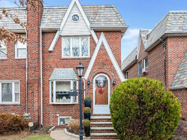 tudor-style house featuring a high end roof and brick siding