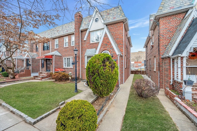 view of front of property with brick siding, a high end roof, mansard roof, and a front lawn