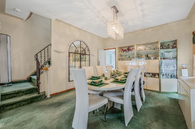 carpeted dining room featuring baseboards, stairs, and an inviting chandelier