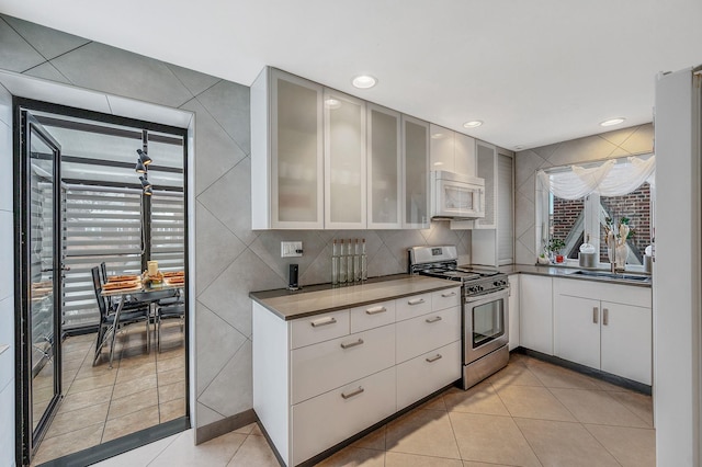 kitchen with white microwave, light tile patterned floors, gas stove, and a sink