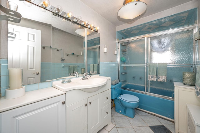 bathroom with vanity, bath / shower combo with glass door, tile walls, toilet, and tile patterned floors