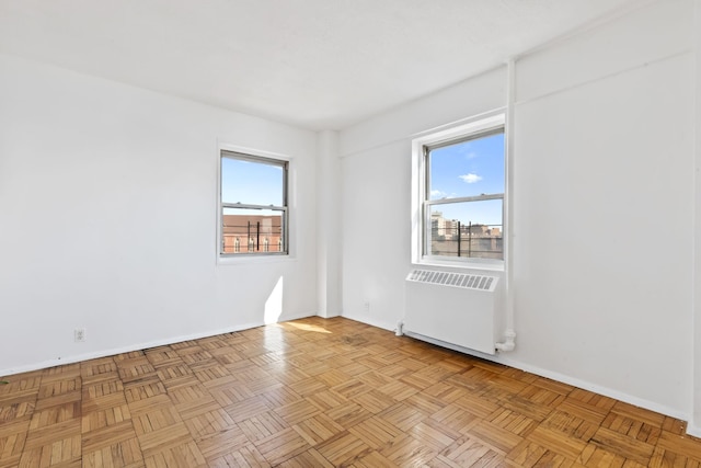 unfurnished room featuring baseboards and radiator