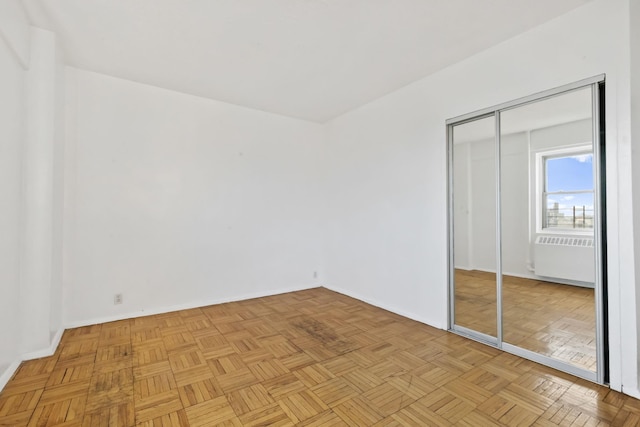 unfurnished bedroom with baseboards, a closet, and radiator