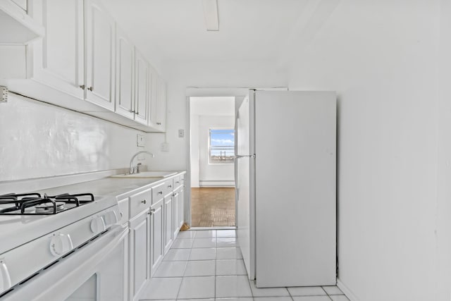 kitchen with light tile patterned flooring, white appliances, a sink, white cabinetry, and light countertops