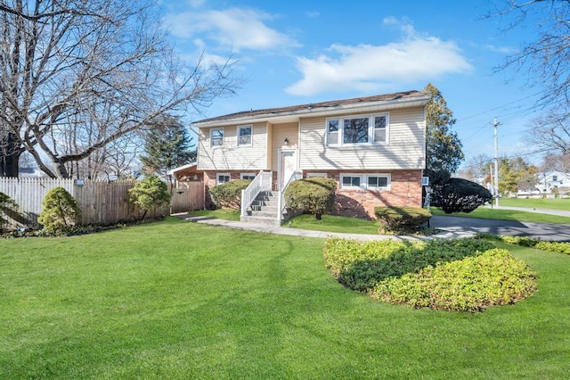 split foyer home with a front yard, fence, and brick siding