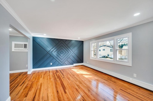 empty room with light wood-type flooring, an accent wall, baseboards, and a wall mounted air conditioner