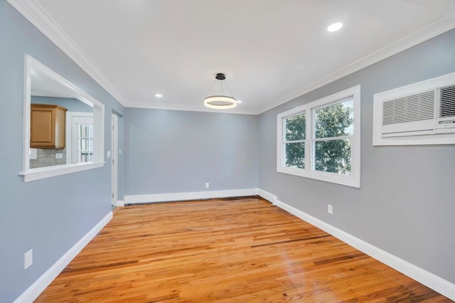 spare room featuring a healthy amount of sunlight, light wood-style flooring, baseboards, and ornamental molding