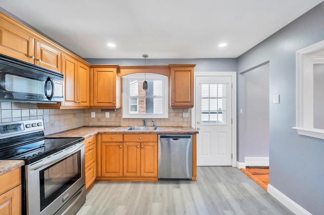 kitchen featuring baseboards, stainless steel appliances, a sink, and light countertops