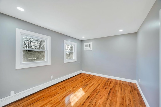 unfurnished room featuring baseboards, a baseboard heating unit, wood finished floors, and recessed lighting