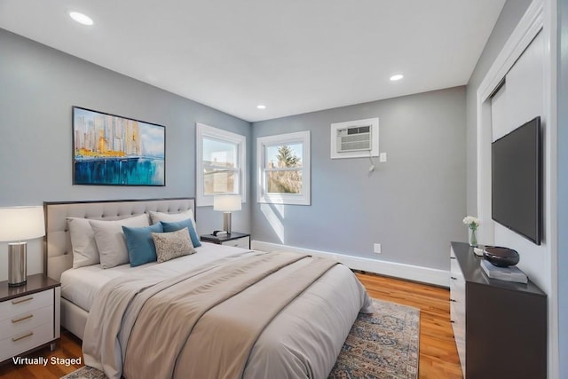 bedroom with recessed lighting, a wall unit AC, baseboards, and wood finished floors