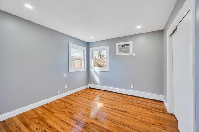 unfurnished bedroom with light wood-style floors, a baseboard heating unit, and baseboards