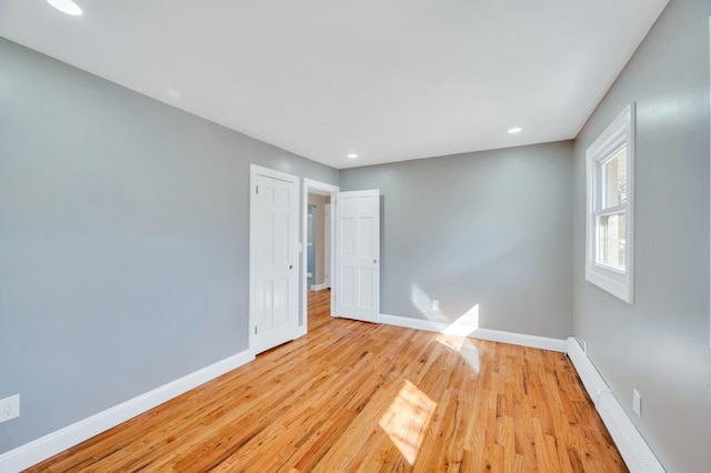 unfurnished room with light wood-style floors, a baseboard radiator, recessed lighting, and baseboards