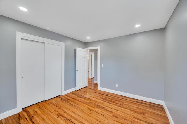 unfurnished bedroom featuring a closet, recessed lighting, wood finished floors, and baseboards