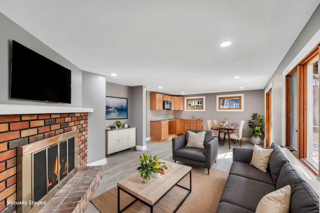 living area with baseboards, light wood-style floors, a fireplace, and recessed lighting