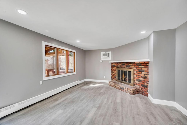 unfurnished living room with baseboards, a baseboard radiator, wood finished floors, a fireplace, and recessed lighting