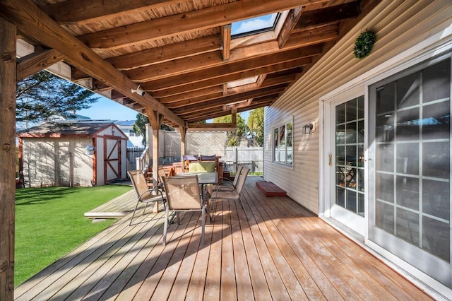 deck featuring outdoor dining area, a yard, fence, a shed, and an outdoor structure