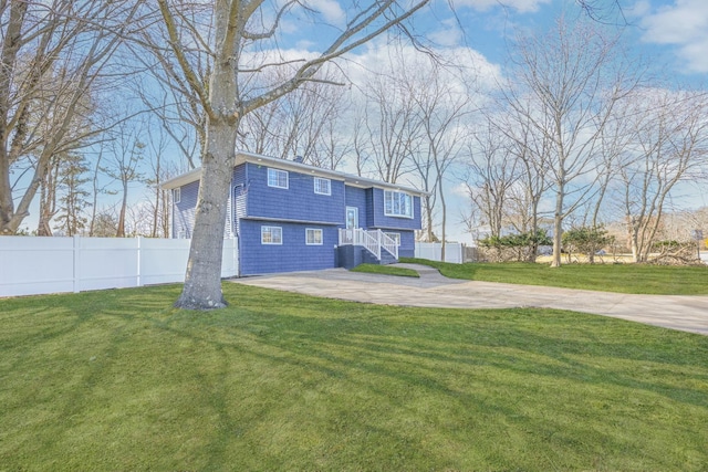 view of front facade featuring central AC, a front yard, fence, and driveway