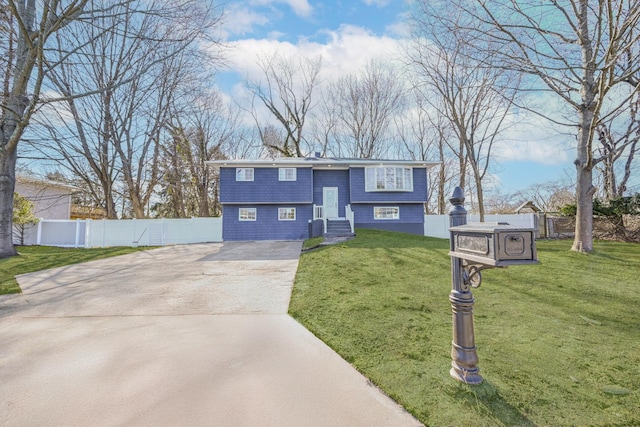 split foyer home with concrete driveway, fence, and a front lawn