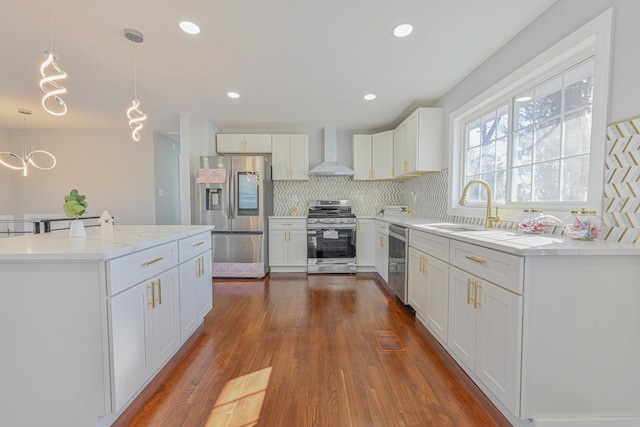 kitchen featuring tasteful backsplash, wall chimney exhaust hood, dark wood-style flooring, stainless steel appliances, and a sink