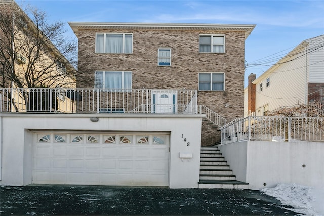 view of property with a garage, brick siding, and stairs