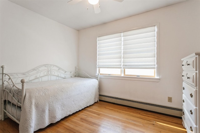 bedroom with a ceiling fan, baseboard heating, and wood finished floors