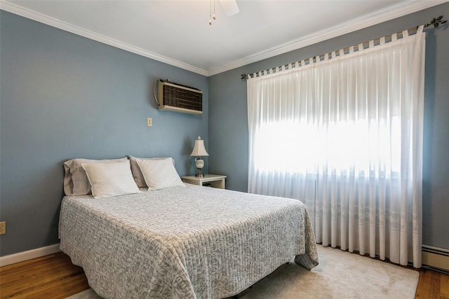 bedroom featuring baseboards, a wall unit AC, ceiling fan, ornamental molding, and wood finished floors