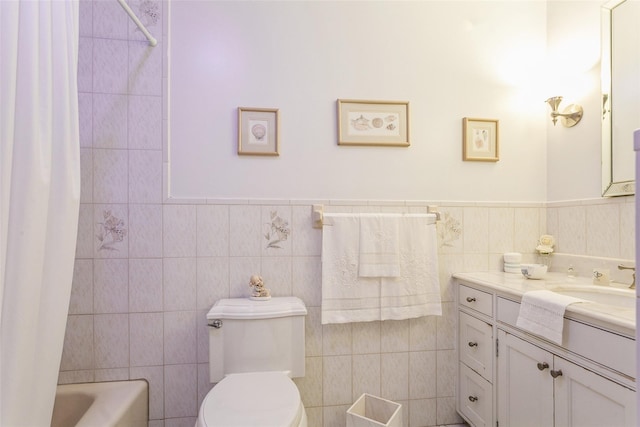 bathroom featuring toilet, a wainscoted wall, tile walls, and vanity