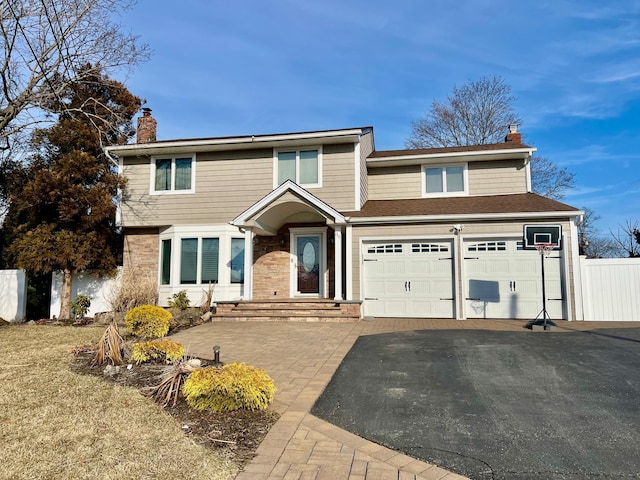 view of front of property featuring a garage, driveway, a chimney, and fence