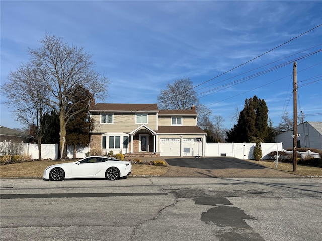 view of front facade featuring an attached garage, driveway, a chimney, and fence