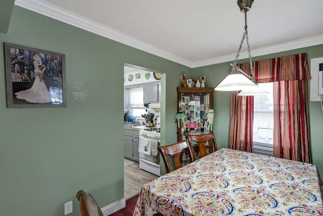 bedroom with ornamental molding, multiple windows, ensuite bath, and wood finished floors