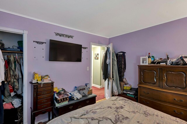 carpeted bedroom with baseboards, ornamental molding, and a closet