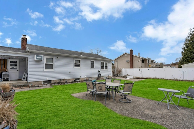 back of house featuring a yard, a fenced backyard, a patio, and a chimney