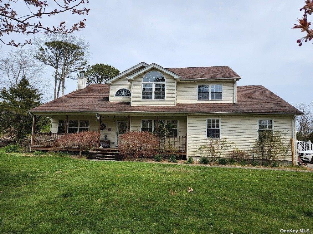 view of front of property with a front lawn, a chimney, and a porch