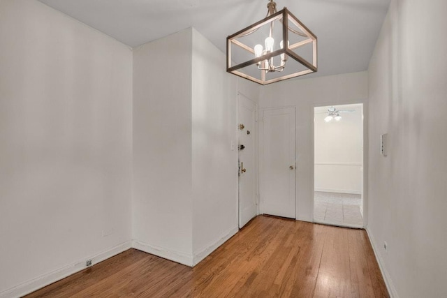 foyer with baseboards, light wood finished floors, and an inviting chandelier